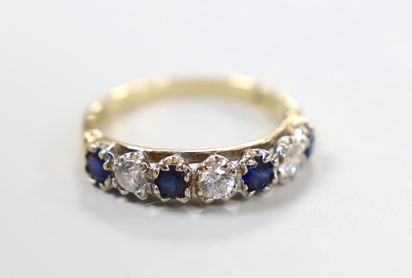 A modern 14ct gold and two colour sapphire? set half hoop ring, size K/L, gross weight 2.3 grams.